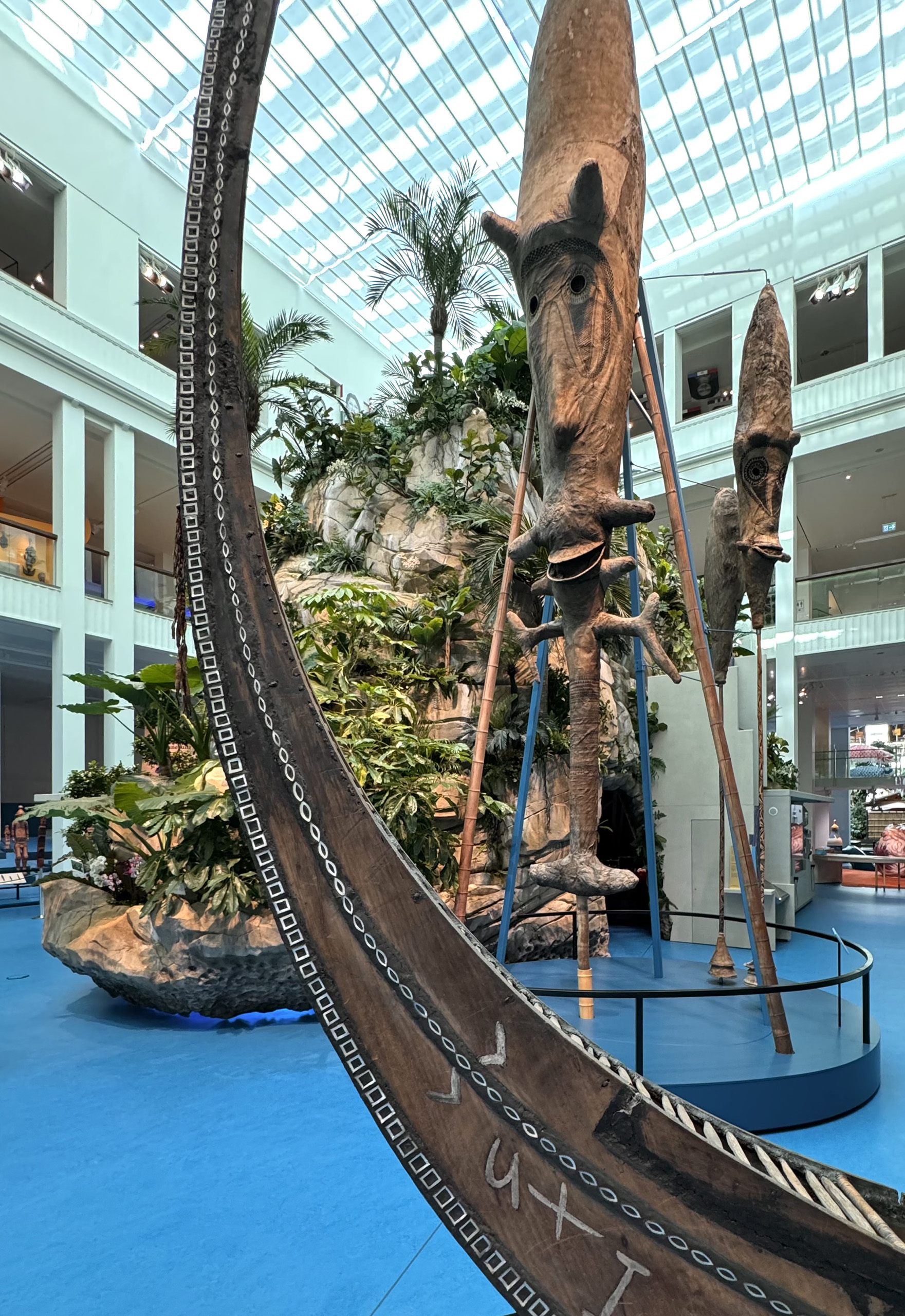Part of the exhibition showing a blue floor, a large statue and rocks and plants