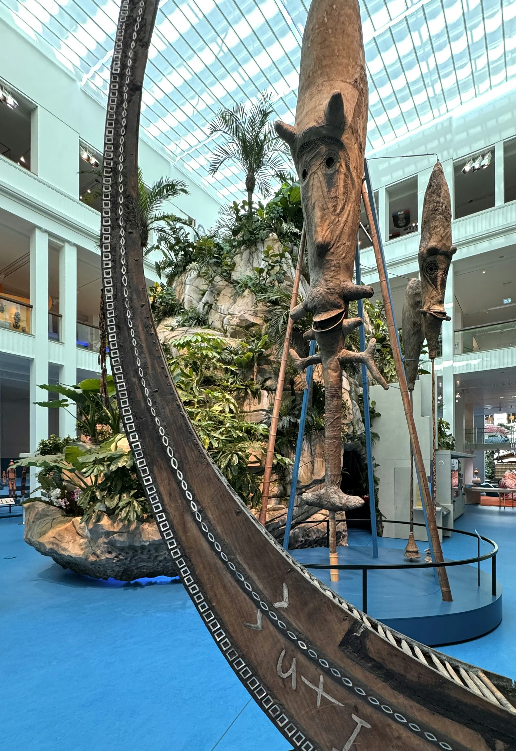 Part of the exhibition showing a blue floor, a large statue and rocks and plants